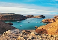 brown and green rock formation on blue sea under blue sky during daytime